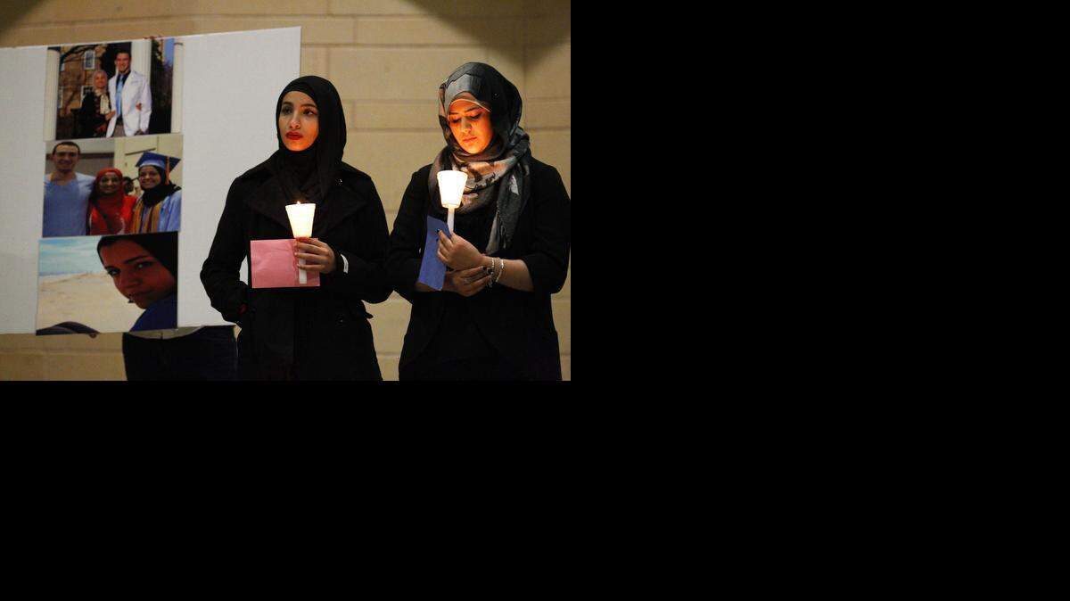 
From left,Nancy Salem and Heba Asi stand next to photos of the three Muslim students who were killed in Chapel Hill, N.C. A candlelight vigil at Levitt Pavilion in Arlington Sunday showed support for the families of the slain students.
