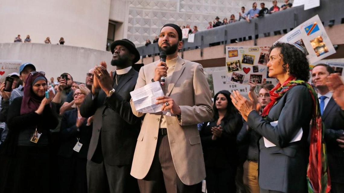 Imam Omar Suleiman speaks flanked by Dr. Michael W. Watson, left, and Rabbi Nancy Kasten, all from Faith Forward, at a vigil for refugees on Jan. 30 in Dallas. A prominent Dallas-area imam, Suleiman, has received at least two death threats in lengthy videos that appear to come from the violent extremist group known as ISIS or Islamic State.