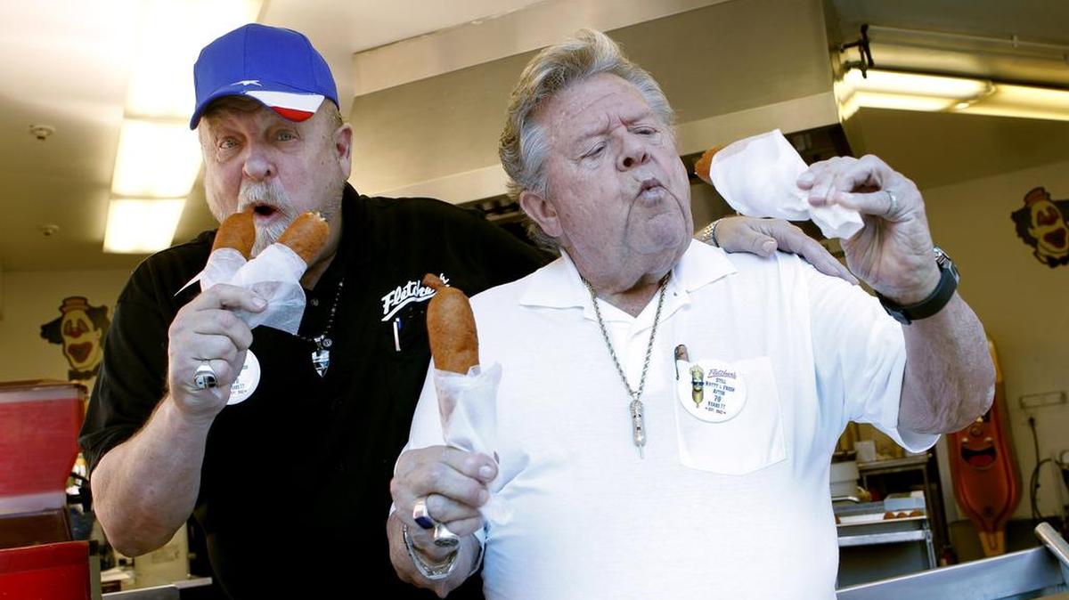 Fletcher brothers, Bill, left, and Skip, right, taste test their first corny dogs on the 70th anniversary of the corny dog at the main Fletcher Corny Dog stand at the State Fair of Texas Sept. 26, 2012.