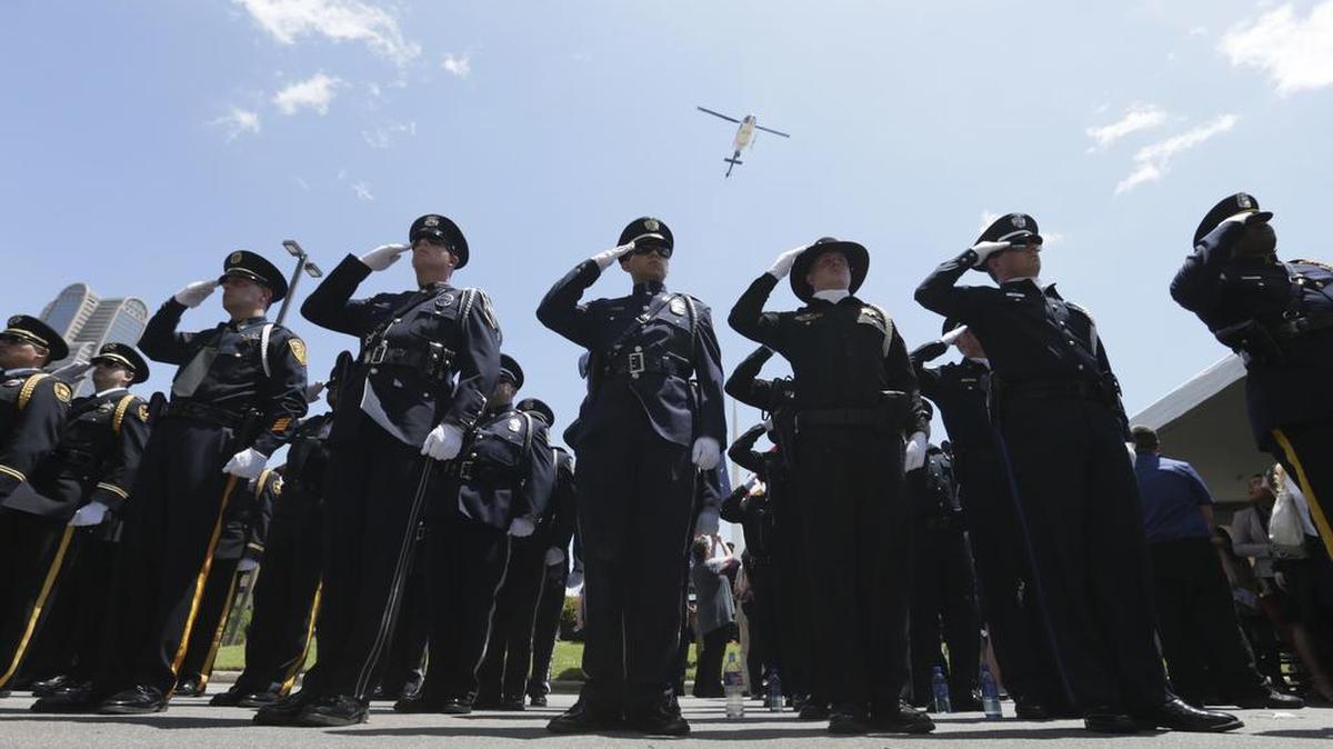 Peace officers from various agencies salute during a memorial service Wednesday for fallen police in downtown Dallas. The Dallas Police Department and city leaders held a ceremony to honor fallen officers as part of the annual Police Memorial Day, less than a year after five officers were slain.