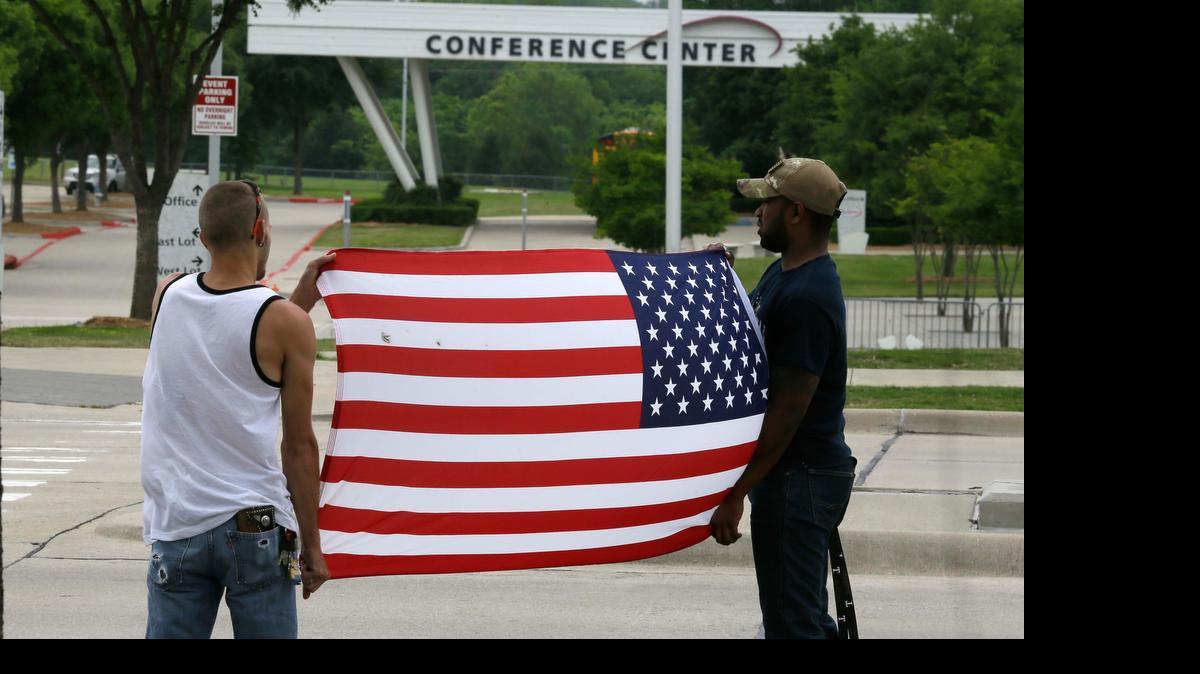 
Joseph Offutt, right, and Conner McCasland hold a U.S. flag across the street from the Curtis Culwell Center Tuesday in Garland. 
