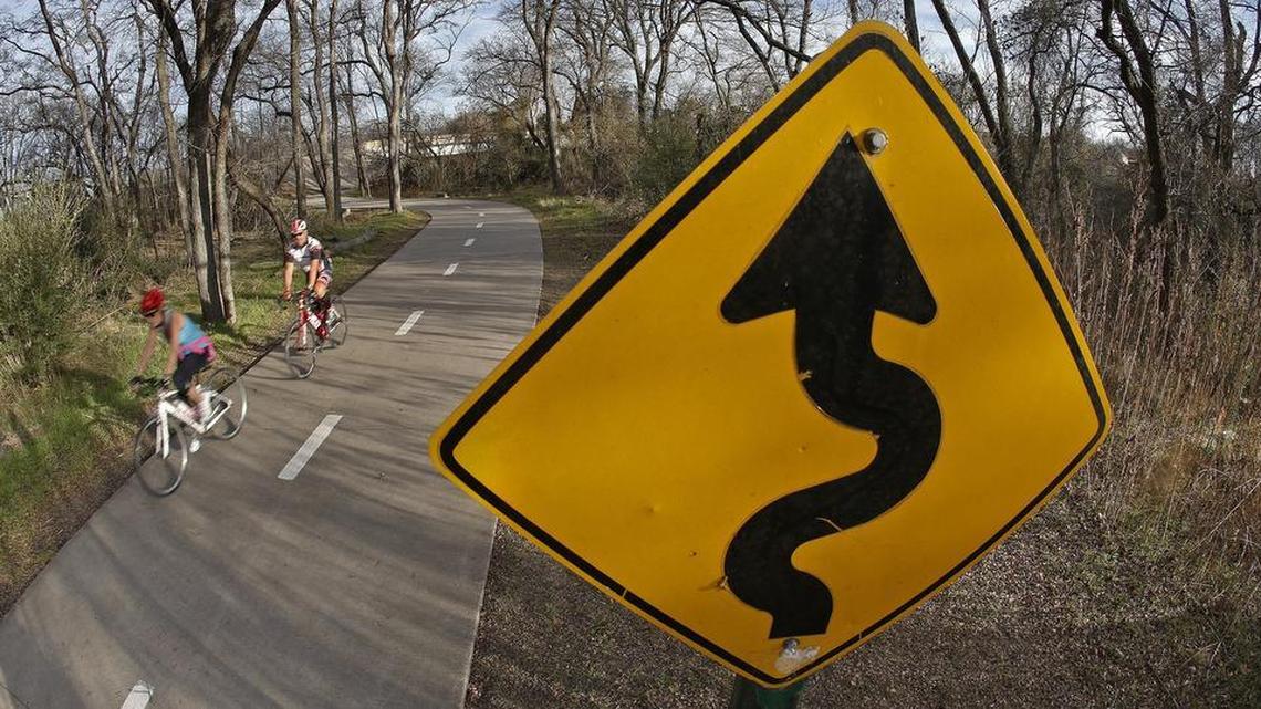 Cyclists ride on the River Legacy path on the east side of the park near the north Collins Street bridge in
