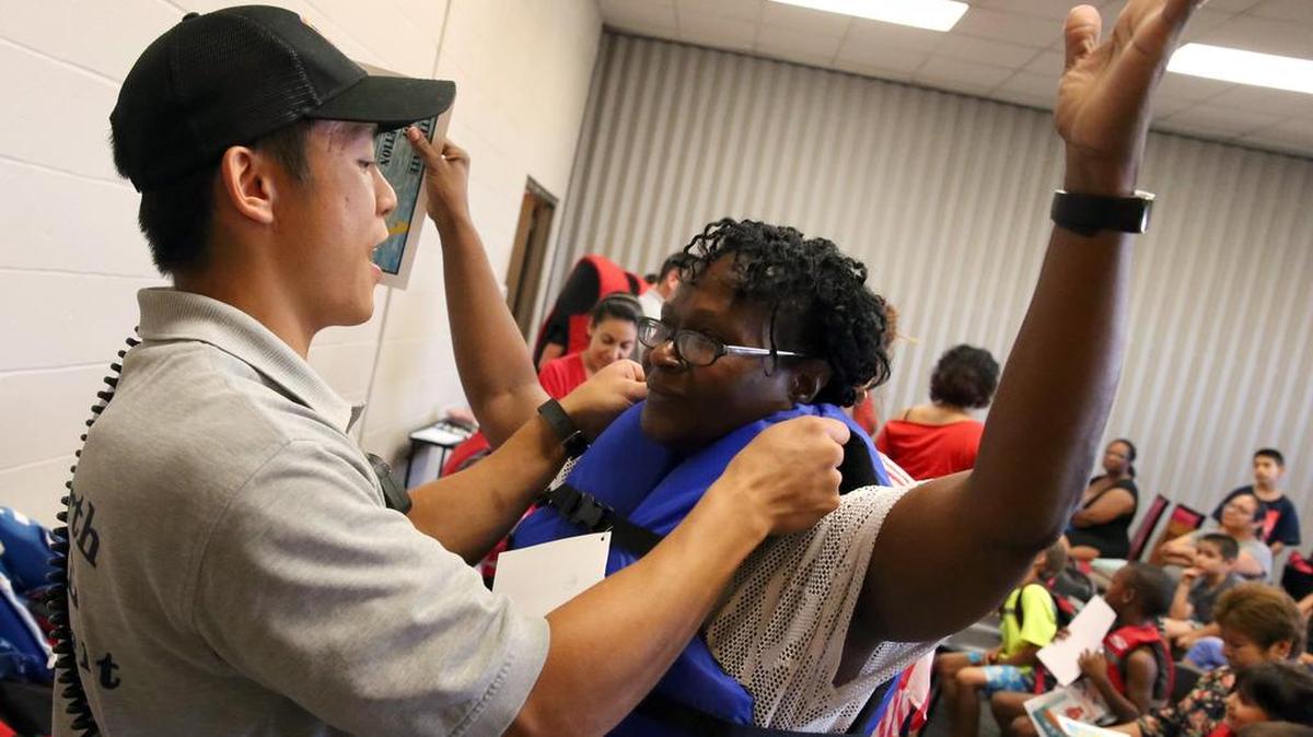 Fort Worth firefighter MH Ngyen fits Laquita Clark with a new life jacket after she completed a class by the Fort Worth Drowning Prevention Coalition at Westside YMCA last week.