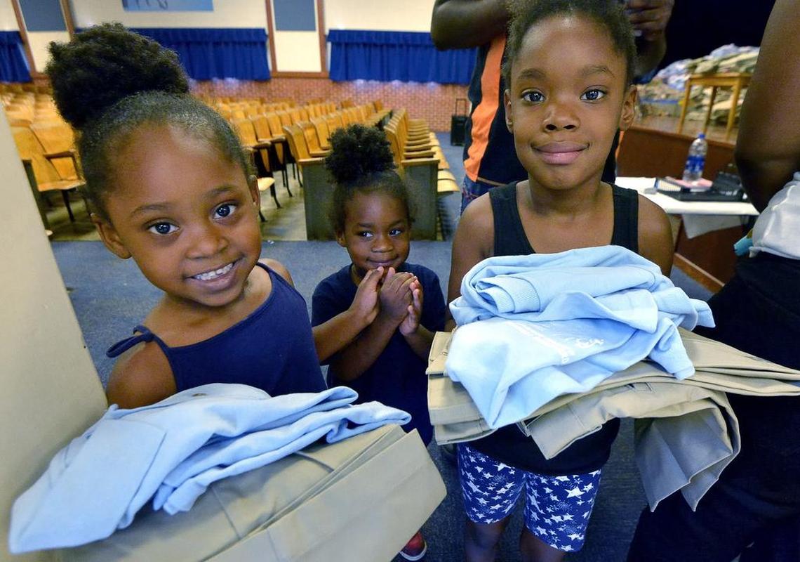 Destiny Davis, 4, left, and her sister Dynasti Davis, 6, received their new uniforms at Leadership Academy at Mitchell Boulevard earlier this month. Their little sister Deja Davis, 3, looks on.