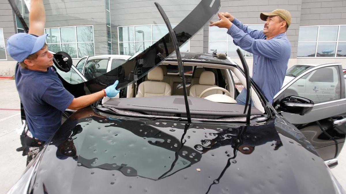 Brandon Jauernig, left, and Juvenal Hernandez of Auto Glass Center replace a windshield on a vehicle damaged by hail storm at MedStar's main office in west Fort Worth.