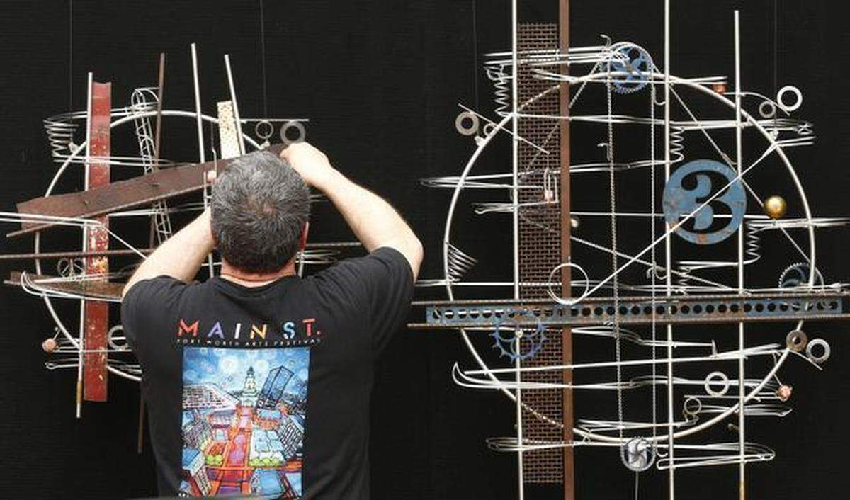 Minnesota artist Jeffrey Zachmann places his kinetic sculptures on the outside of his tent while setting up for the opening of the Main Street Arts Festival in April 2015.