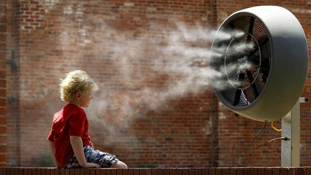 
Max Neal, 4, of Roanoke cools off in front of a water-spraying fan in the Stockyards as he waited with his family for the daily cattle drive in Fort Worth. 
