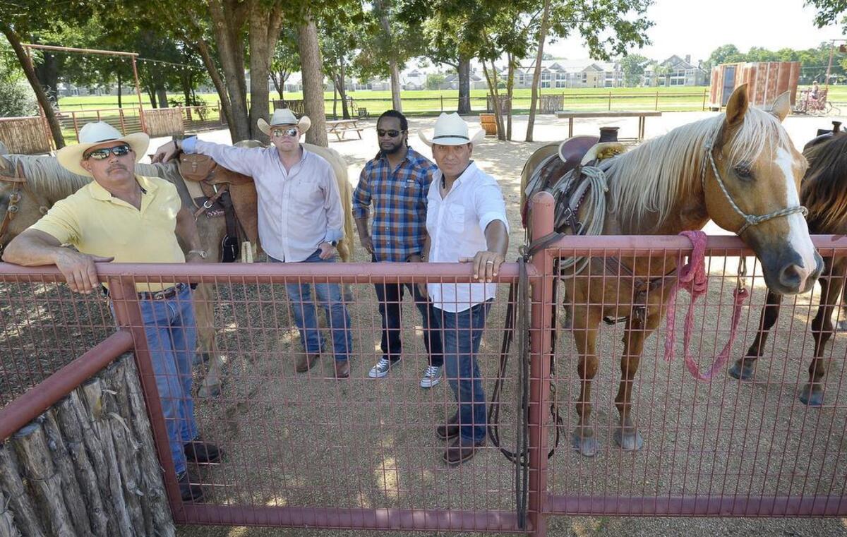 Steve Sexton, Chris Campbell, Andy Williams and Joel Medina tie their horses to a fence along the Trinity Trail in Fort Worth.