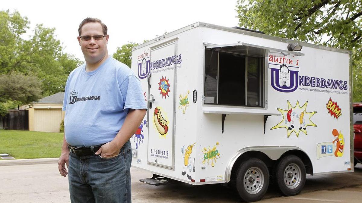 Austin Underwood has Down syndrome. He stands next to his food truck that serves specialty hot dogs.