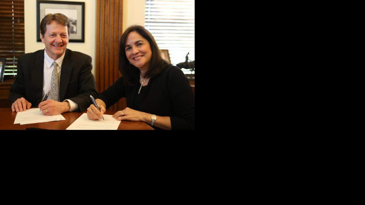 
Marjorie Herrera Lewis and Texas Wesleyan President Frederick Slabach sign documents establishing new endowed speakers series. The series will focus on sports. 
