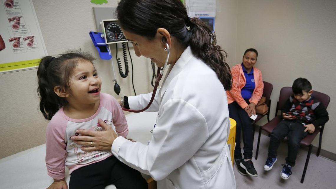 Dr. Jusan Galarza gives a checkup to 3 year-old Brigette Trejo Monday as her mother Arsenia Trejo and Yeray Comacho wait in the exam room at JPS Health Network's Viola Pitts/Como Health Center.
