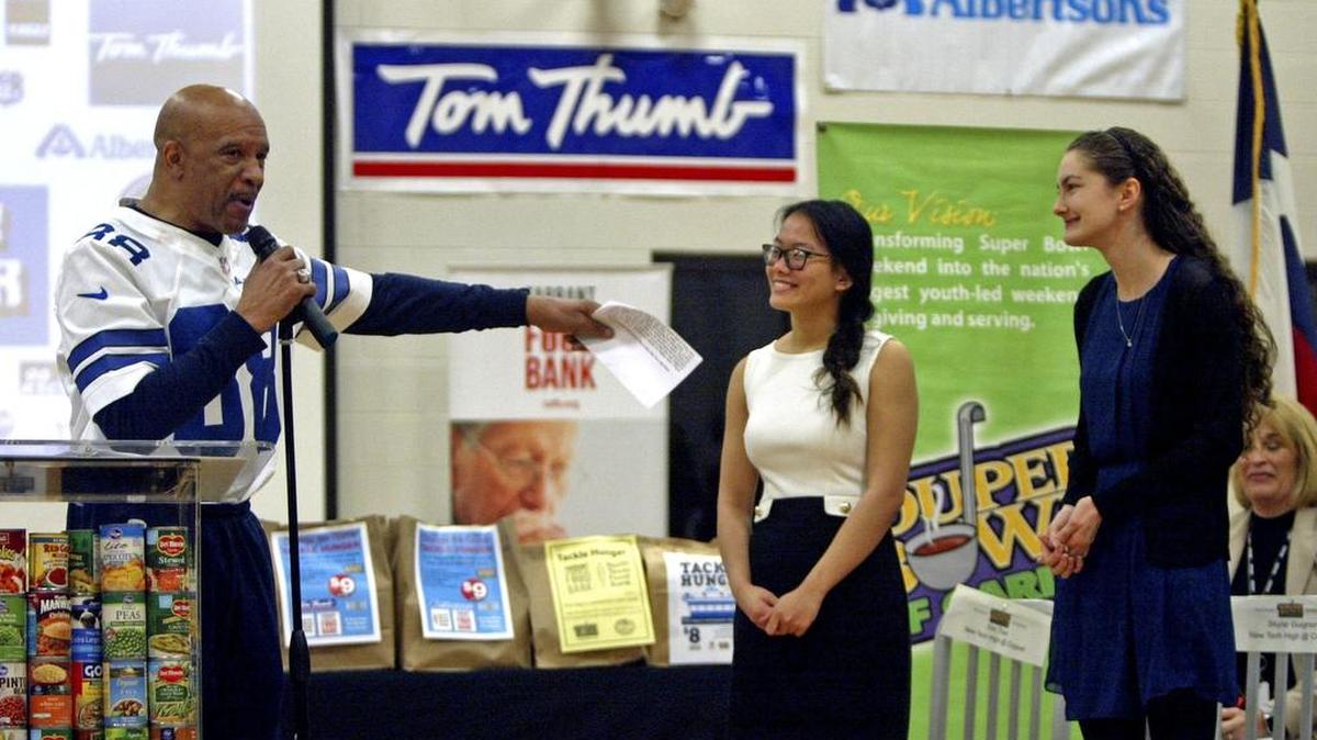 Former Cowboys wide receiver Drew Pearson introduces New Tech High @ Coppell students Kim Tran, 17, and Skylar Guignon, 17, during a Souper Bowl of Caring pep rally Tuesday.
