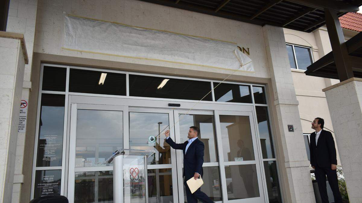 Todd Liles, executive director and trustee of The Morris Foundation, unveils the new sign dedicating The Morris Foundation Building at the Northside Community Health Center. He is joined by Dr. Carlos Morales, board president of the North Texas Area Community Health Centers.
