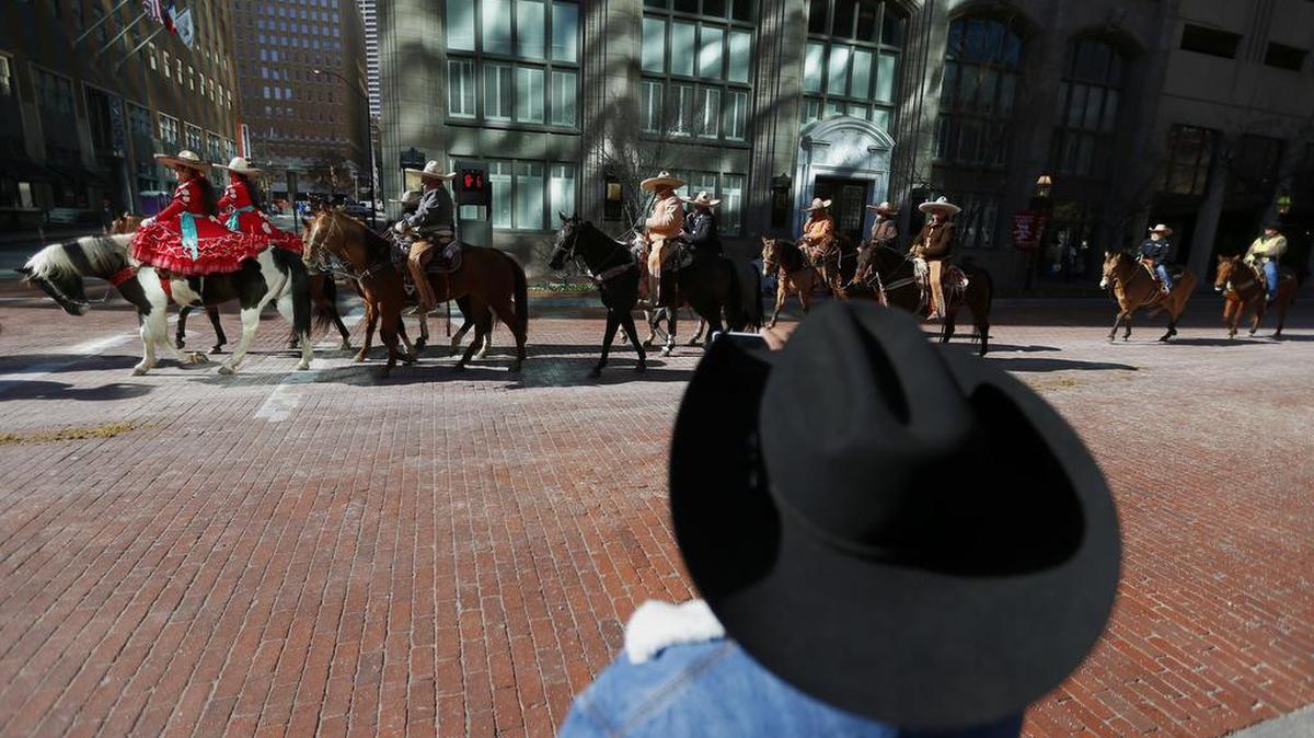 Rudy Juarez watches as Fort Worth Stock Show and Rodeo All Western Parade participants ride down Main Street in Fort Worth on Saturday.