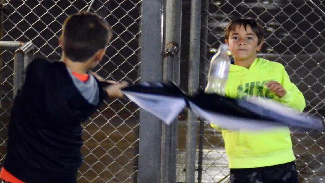 During a rain delay at Friday night’s football game between Fort Worth’s Southwest and South Hills high schools, Jackson Green, left, and Kaden Viola play a little baseball using an umbrella and empty plastic bottle.