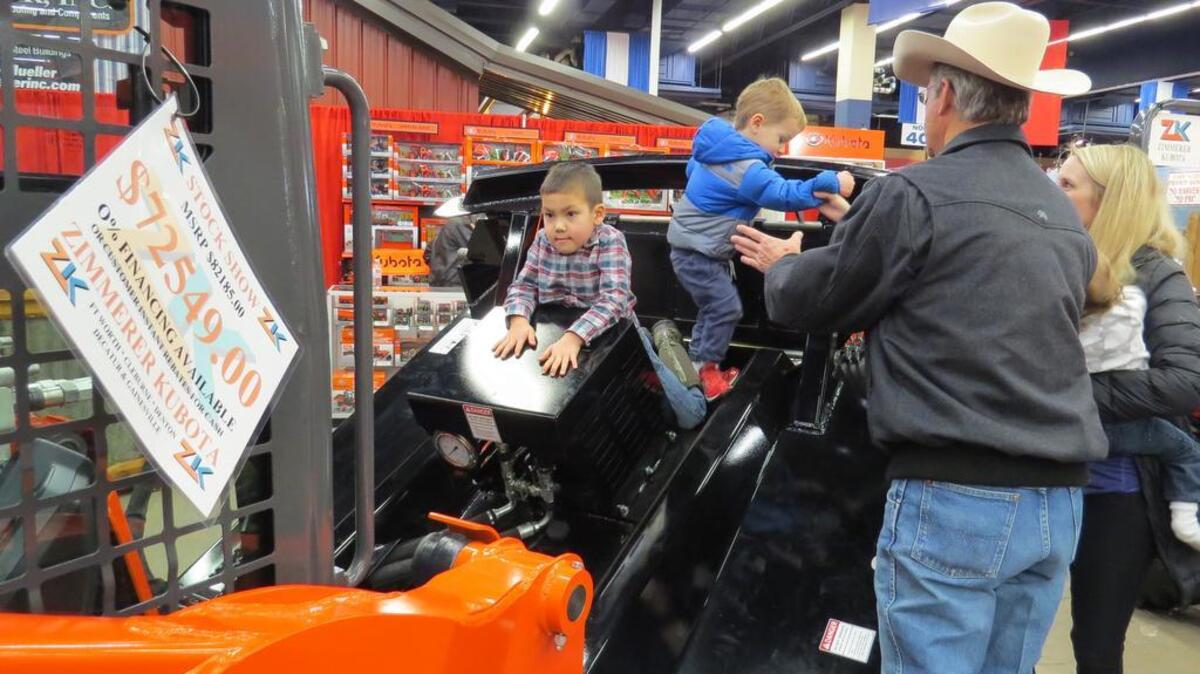 Glenn Rogers of Aledo watches grandsons Braden, left, and Caleb inspect a track loader at the Zimmerer Kubota booth the Fort Worth Stock Show and Rodeo.