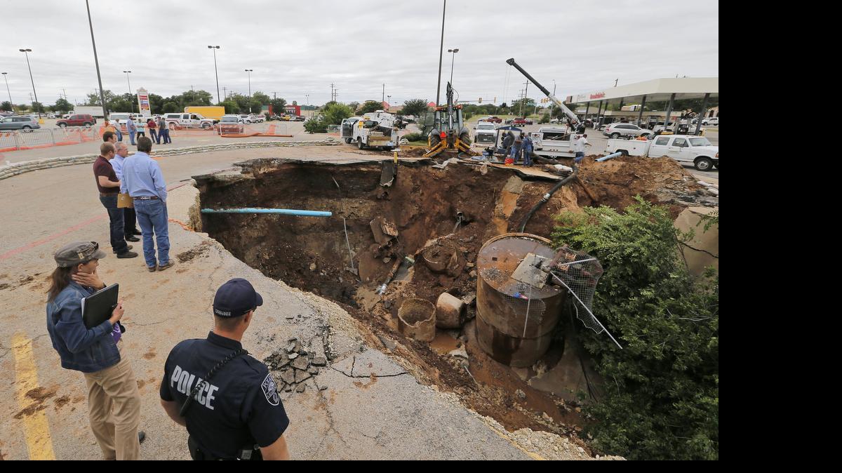 
Granbury safety and public works officials deal with a sink hole that opened up after heavy rains collapsed a storm sewer under the pavement at the edge of a parking lot next to the Brookshire's store on Morgan Street. Workers were stopping the water flow from broken pipes and rerouting water services before attempting to shore up and repair the damage.
