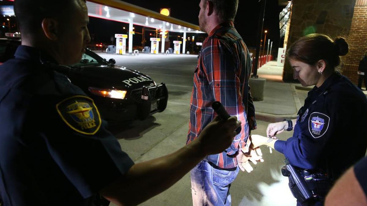 Officer M. Buendia holds a flashlight to assist Officer J. Russell as she arrests a man pulled over on suspicion of driving while intoxicated last month.