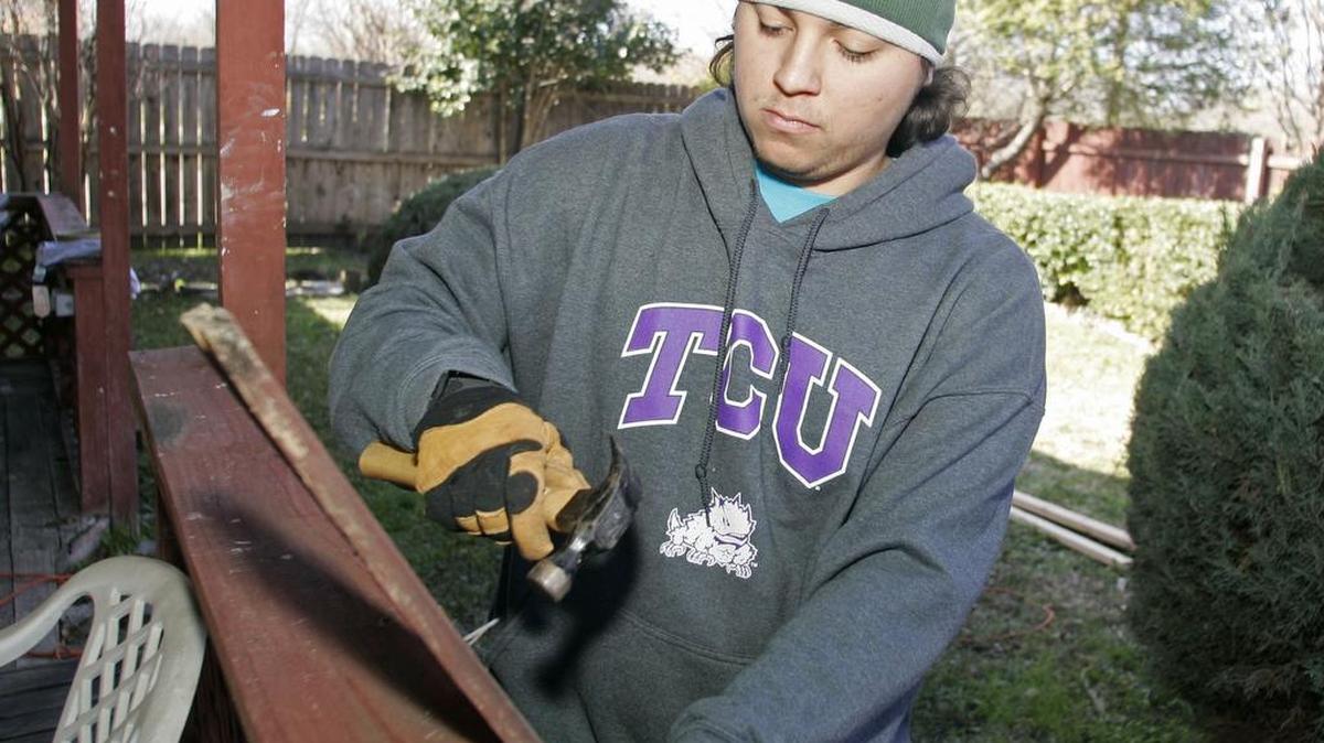 Mirko Murillo removes nails from a rotted wood fence in the Greenway neighborhood on Monday.