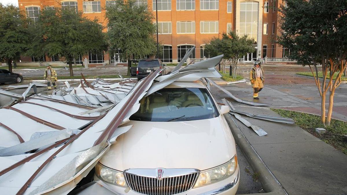 A car is covered in debris after a tornado ripped the roof off the Compass bank building in north Fort Worth on Thursday.