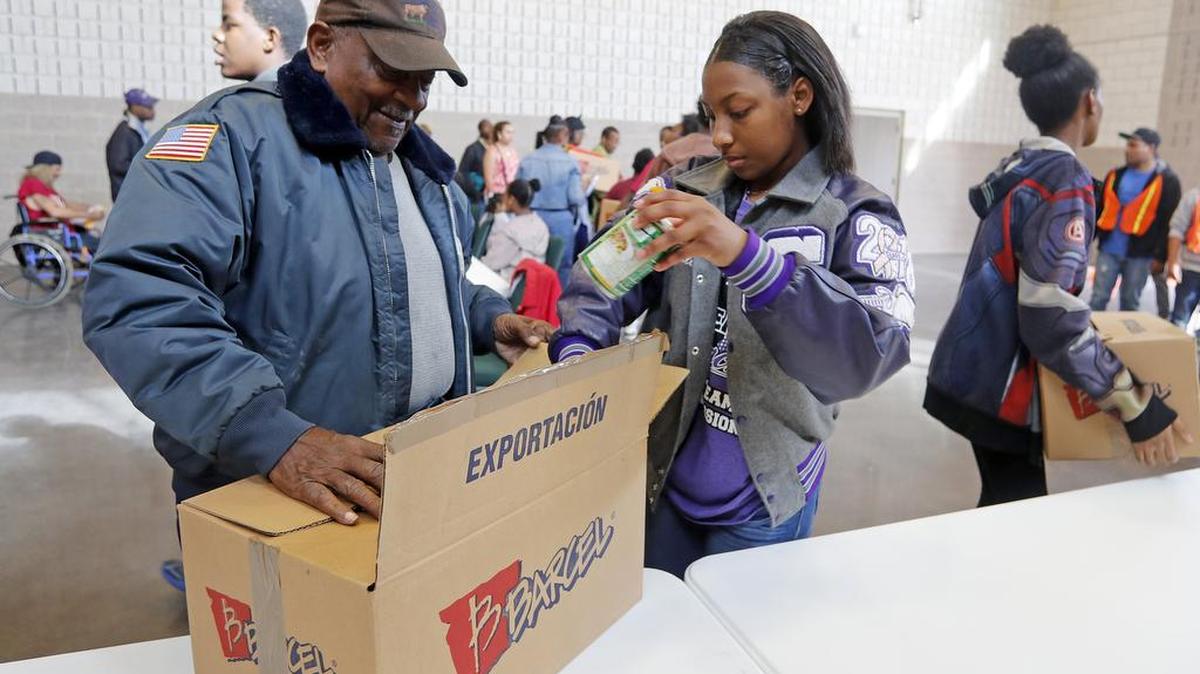 Volunteer Mallory Medlock, 16, helps Johnie Davis with his box of food as families receive Thanksgiving food baskets at Bethlehem Center. Within 1 1/2 hours more than 500 families had received Thanksgiving food baskets, about half the number that organizers said needed the help.