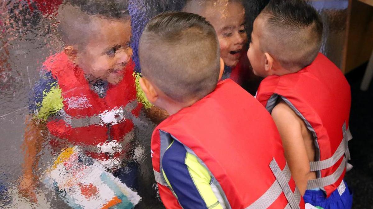 Isaac Garrido,4, and his brother Emilio, 2, admire their new life jackets in on a reflective surface at the Westside YMCA after receiving certificates for completing a class by the Fort Worth Drowning Prevention Coalition last week.