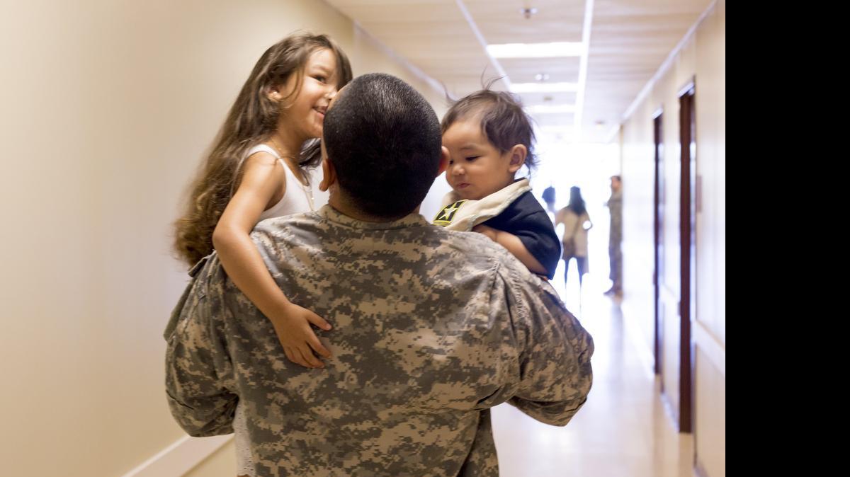 
Mark Parnel bounces his kids, Belle, 4, and Blake, 8 months, in his arms Saturday morning while walking them out of the White Settlement Reserve Center after returning from a tour in Kuwait. 

