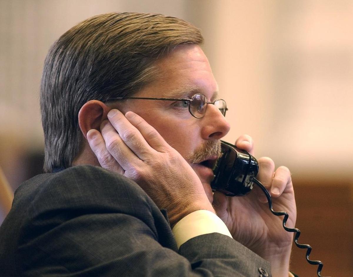 Rep. Phil King, R-Weatherford, talks on the phone from his desk on the floor of the Texas House of Representative in 2003.