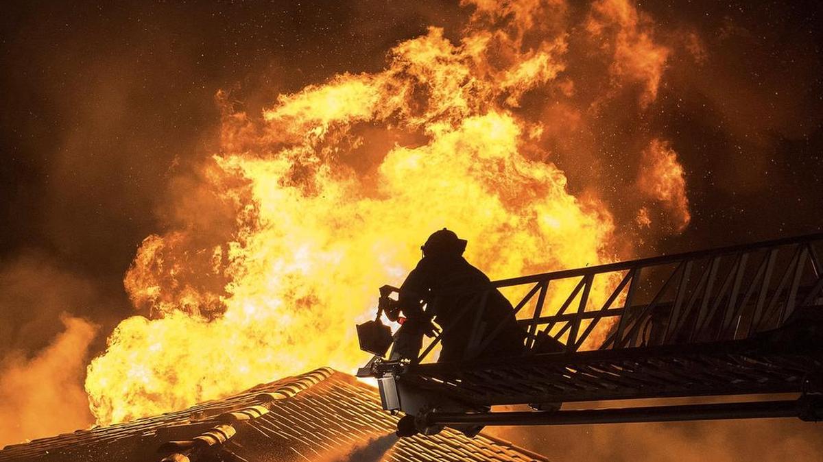 Fort Worth firefighter Mike Leatherwood works from a ladder as heavy fire roars from the attic at at large home at 6509 Haig Point Court early Saturday.