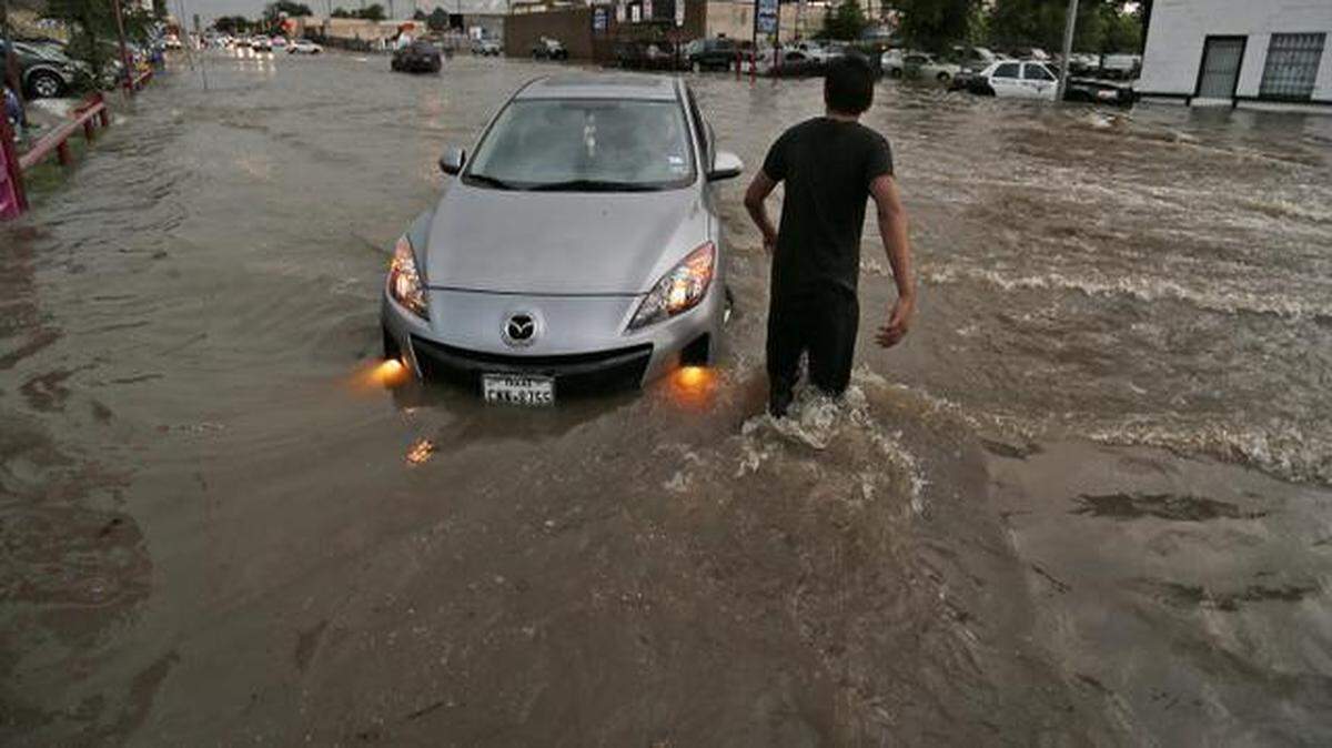 
A man wades out to help a water-logged car in the 3600 block of Hemphill Street in June 2014 after heavy afternoon rains caused major flooding. The city is revising its storm water management manual for developers. 
