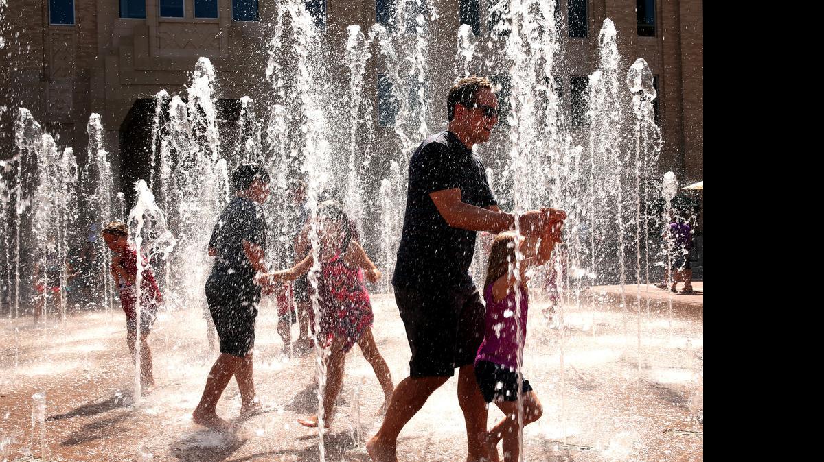 
Downtown visitors cool off in the Sundance Square fountain in Fort Worth as the temperature reached 100 at DFW Airport for the first time this year,
