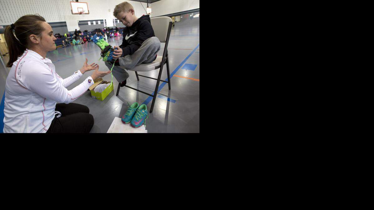 
Fitness and nutrition coach Kelli Crisp fits Trace Adams with new shoes, donated by representatives from the Cowtown Marathon’s Children's Activity Lifetime Fitness project.
