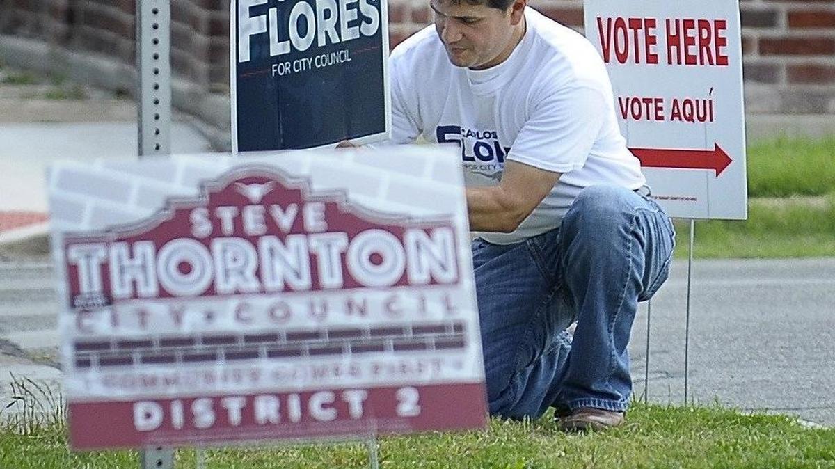 Carlos Flores places a campaign sign at Ruffino Mendoza Elementary School.