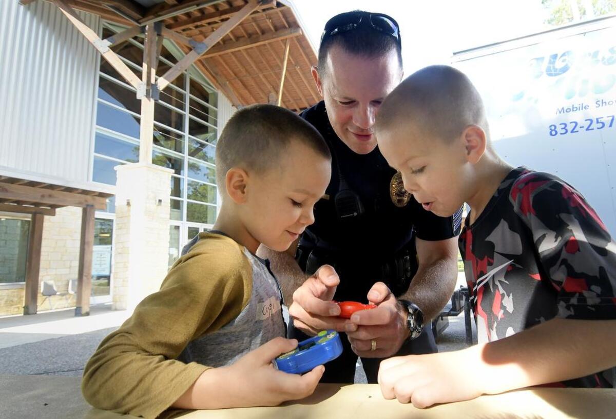 Arlington Policer Sgt. Scott Vickers plays video games with evacuees Cayden and Camron Pelletier at Red Cross shelter in Conroe.