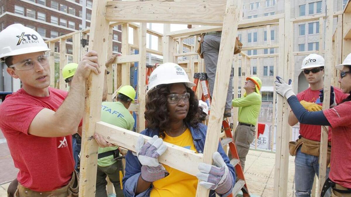 XTO volunteer Jonathan Kumpa, left, helps build a Habitat for Humanity house for Tayilo Ngalasa, center, on Tuesday in Sundance Square.