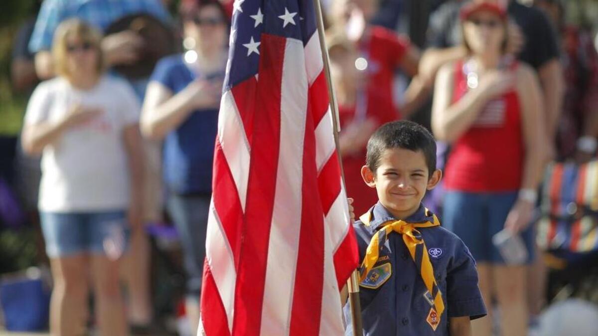 Zachary Nelson, 7, a Cub Scout from Pack 235, holds an American flag during the National Anthem at the Arlington Fourth of July parade, Saturday, July 4, 2015.