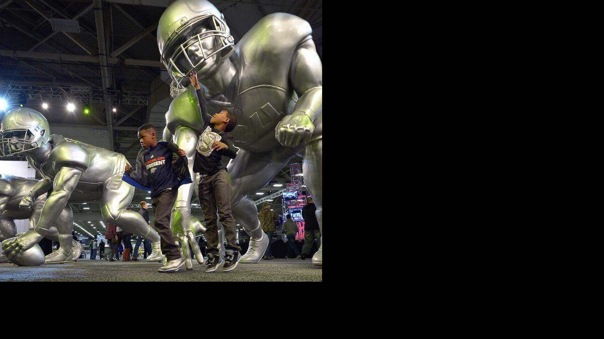 
Twins Jhayden, right, and Kahtori Crawl, 8, stop to have a photo taken with the larger-than-life football players at the College Football Playoff National Championship Experience at the Kay Bailey Hutchison Convention Center in Dallas Friday, Jan. 9, 2015. 
