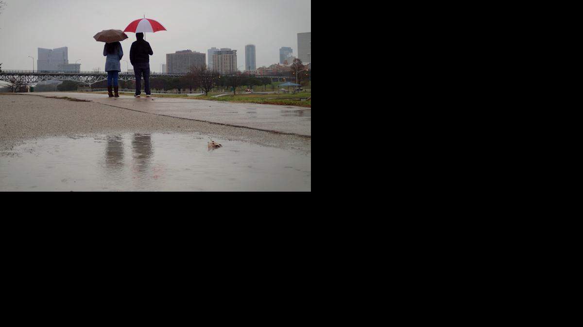 Violeta Avina and Luis Segarra, both of Dallas, watch the rain in Trinity Park. 2014 will likely be the 13th-driest year on record in North Texas.<137> after spending the day at the Fort Worth Zoo, Wednesday, December 17, 2014. (Star-Telegram/Rodger Mallison)<137>