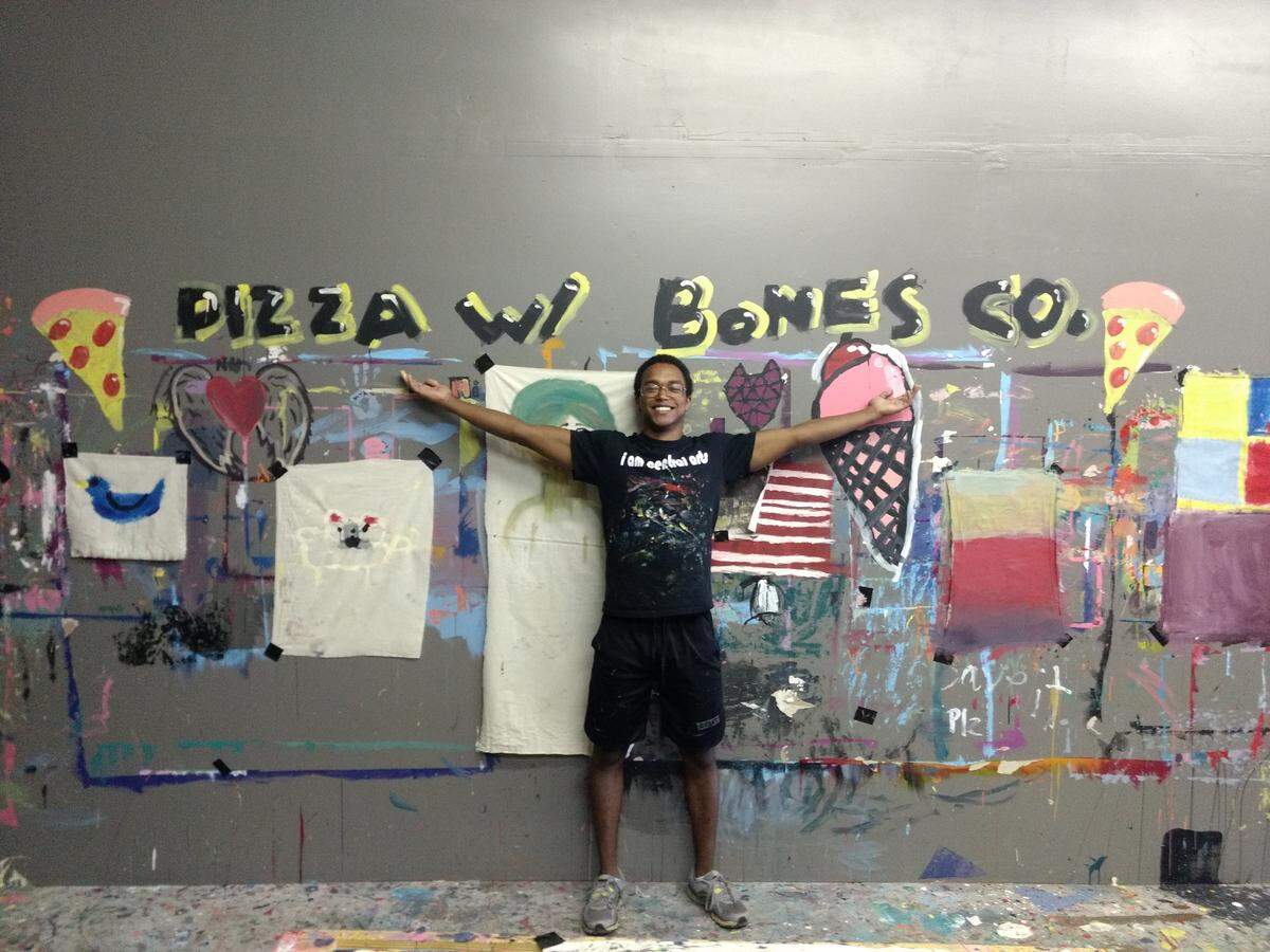 Mohammed Sahil, a volunteer with the nonprofit Equal Hearts, stands in front of student work.