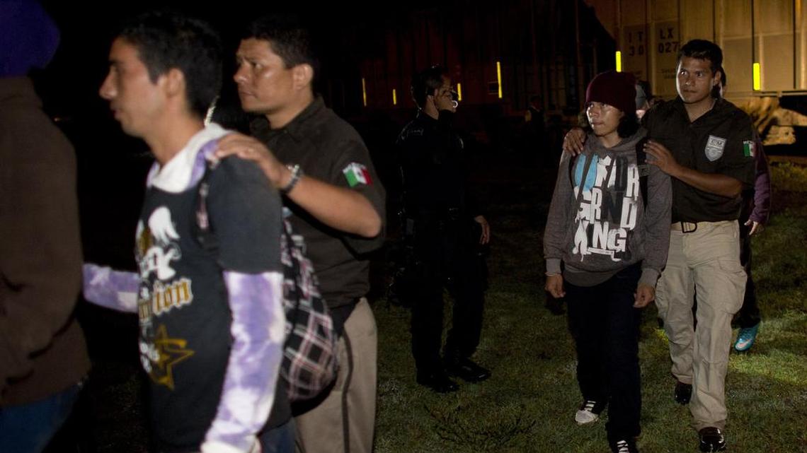 FILE: Immigration officers lead migrants, including a boy, second from right, to a holding van during a raid by federal police on a northbound freight train in San Ramon, Mexico, just after midnight on Friday, Aug. 29, 2014. Migrants captured in police raids are held for deportation to their home countries. The largest crackdown by Mexican authorities on illegal migration in decades has decreased the flow of Central American migrants trying to reach the United States, and has dramatically cut the number of child migrants and families, according to officials and eyewitness accounts along the perilous route.(AP Photo/Rebecca Blackwell)