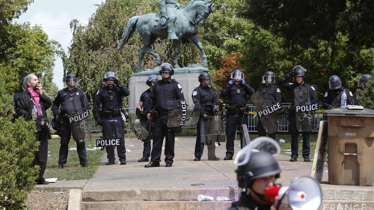 State Police in riot gear guard Lee Park after a white nationalist demonstration was declared illegal and the park was cleared in Charlottesville, Va., Saturday, Aug. 12, 2017. Hundreds of people chanted, threw punches, hurled water bottles and unleashed chemical sprays on each other Saturday after violence erupted at the white nationalist rally.