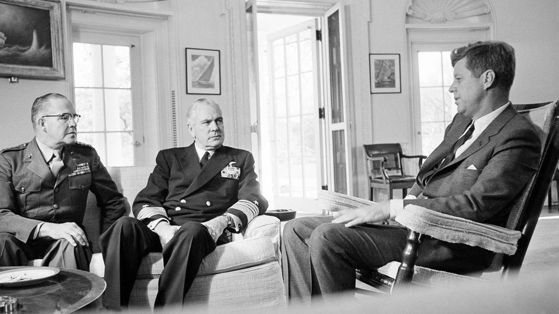 
File: In this Oct. 29, 1962, file photo, President John F. Kennedy poses in the White House office with Gen. David Shoup, left, Marine Corps Commandant, and Adm. George Anderson, Chief of U.S. Naval Operations in Washington. The chiefs met with the president to review the situation in Cuba and operation of the U.S. naval blockade. As the U.S. and Russia reached the brink of nuclear war in 1962, Kennedy received top-secret intelligence from the CIA that a new warhead launcher was spotted in Cuba. That report, given to Kennedy a day before the end of the Cuban Missile Crisis, is among roughly 19,000 pages of newly declassified CIA documents from the Cold War released Wednesday, Sept. 16, 2015. (AP Photo/William J. Smith, File)
