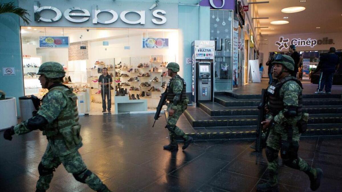 Soldiers walk inside Plaza Las Americas mall following reports of gunfire in Cancun, Mexico, Tuesday, Jan. 17, 2017. Gunmen attacked the state prosecutor's office in this Caribbean resort city Tuesday, ratcheting up tensions just a day after a deadly shooting at a music festival in a nearby town.