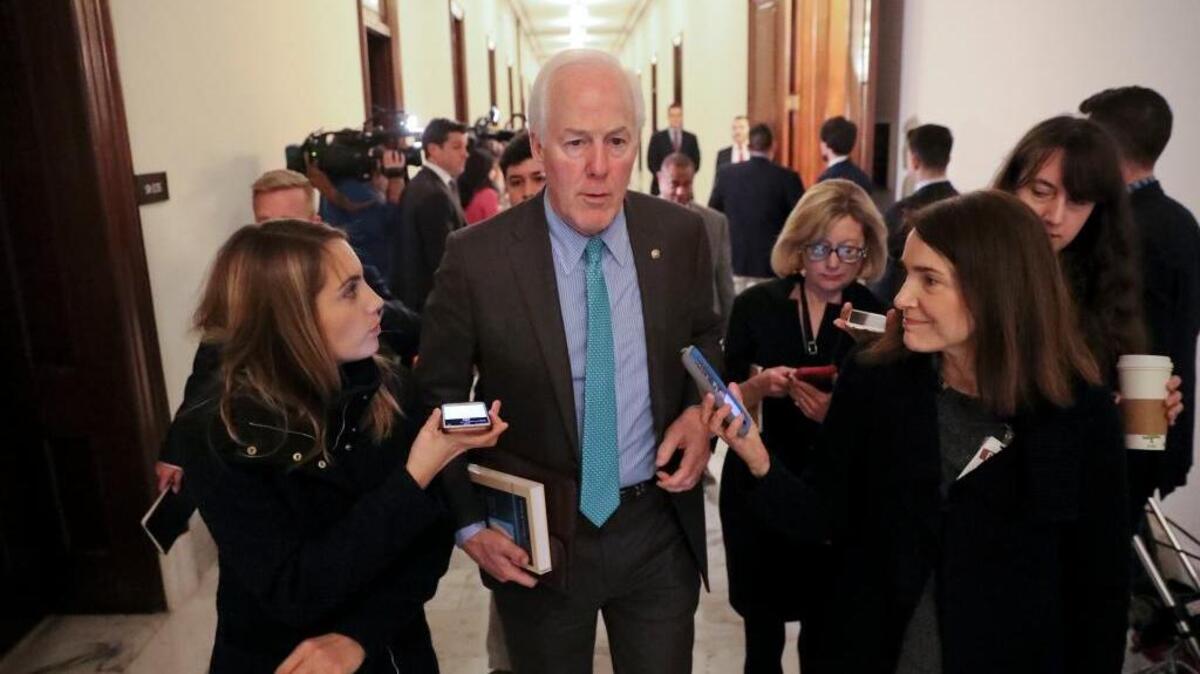 Senate Majority Whip Sen. John Cornyn, R-Texas, center, is questioned by members of the media after attending a meeting on immigration with other senators.