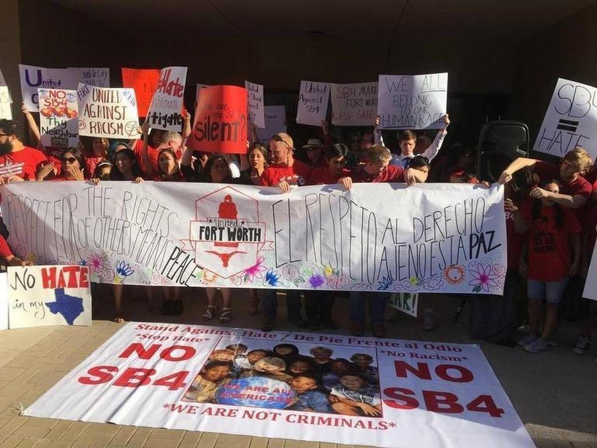Protesters held signs expressing their displeasure against Senate Bill 4 before a Fort Worth city council meeting in June.