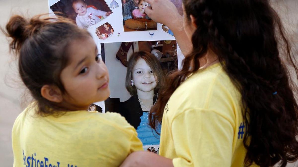 Sisters Yuselei and Lluviana Monroy look over photos of Leiliana Wright prior to a candlelight vigil for Leiliana at Katherine Rose Memorial Park in Mansfield on April 10.