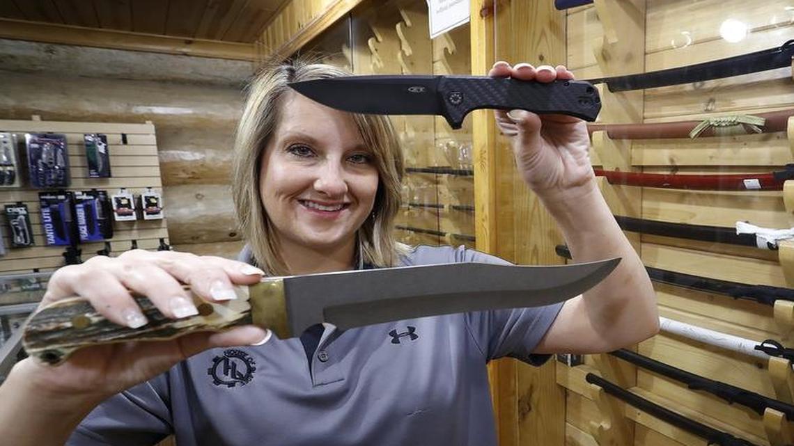 Misty Thomas holds a legal everyday carry folding knife (top) and one of the store's larger Bowie knives (bottom). The staff at House of Blades in west Fort Worth, show some of the currently-legal knives, as well as some larger items that will be legal in Texas as of September 1.