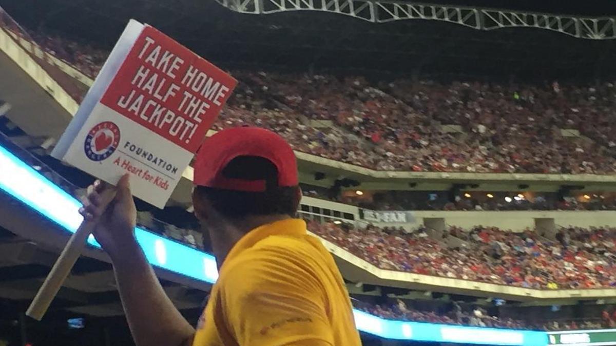 Signs such as these, offering fans the chance to “Take Home Half the Jackpot,” were carried around the stands last season at home games for the Texas Rangers. It was a way to promote the 50-50 charitable raffles — and give fans a chance to buy tickets from their seats.