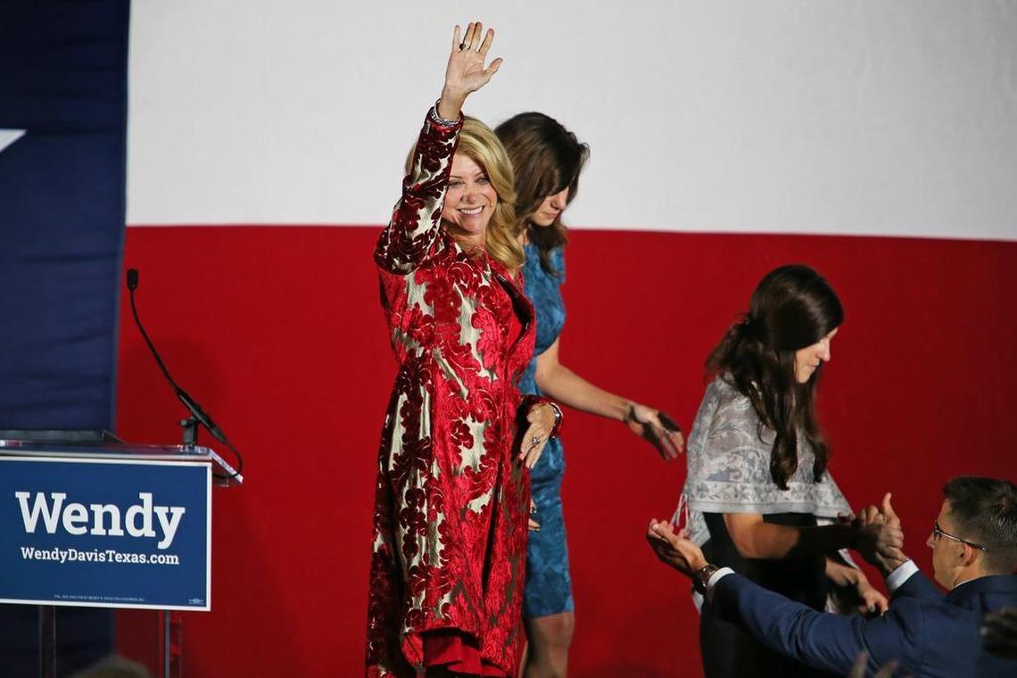 Wendy Davis waves goodbye as she leaves the stage with daughters Dru Davis, center, and Amber Davis after conceding the election to Greg Abbott in 2014.