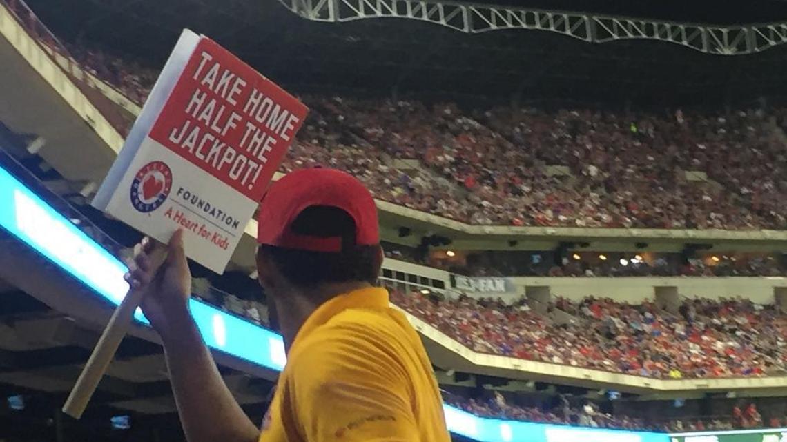 Signs offering fans the chance to “Take Home Half the Jackpot” are carried around at home games for the Texas Rangers, giving fans a chance to buy raffle tickets from their seats.